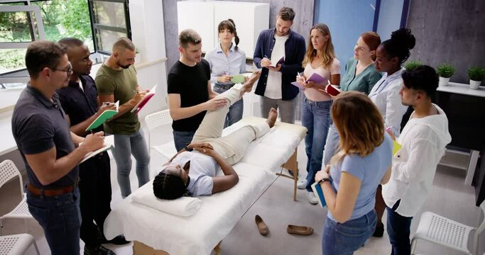Male Instructor Teaching Massage Technique To Group