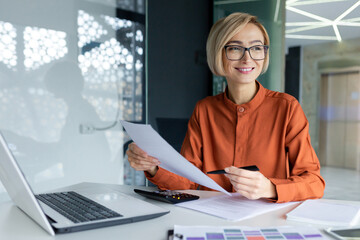 Young successful business woman working inside office with documents, woman satisfied with...