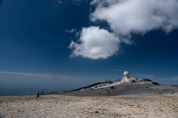 The top of the Mont Ventoux in Vaucluse,  a man takes readings near the Radôme, a civil aviation radar. A blue sky.