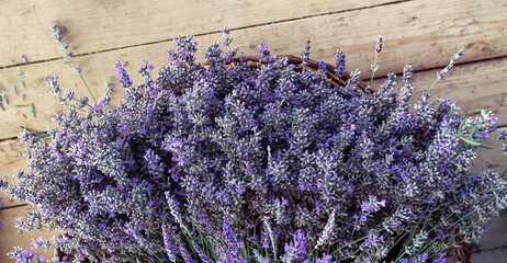Bouquet of fresh lavender flowers in a basket at background of wooden boards, top view. Lavender season in Provence. - 627789667