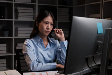 Focused and stressful young businesswoman trying to concentrate on her project while working overtime at night.