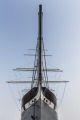 An old sailing boat with a small rainbow flag picture taken from underneath of the bow. 