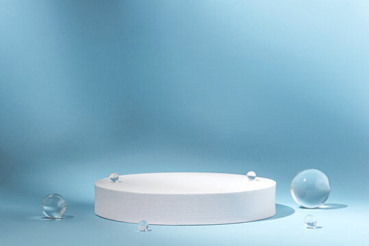Fototapeta White podium with glass balls on a blue background for product presentation. Minimal concept and hard sunlight.