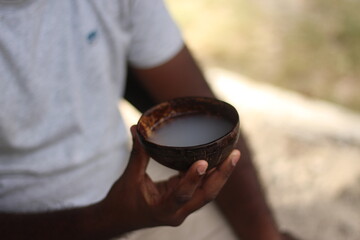 person with a cup of  palm alcohol 