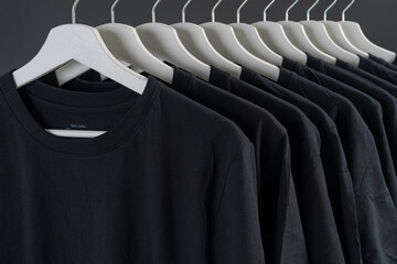 Close-up of black t-shirts on hangers, a collection of black t-shirts hang on a wooden clothes...
