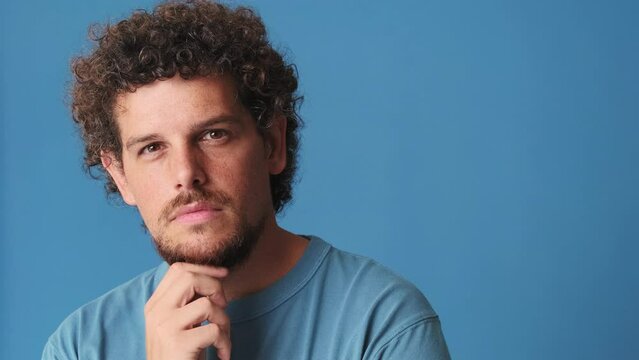 Close up, pensive man thinks something, isolated on blue background in studio