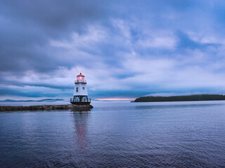 Le phare de Burlington avant le coucher de soleil sous un ciel chargé de nuages qui laissent percés un ciel bleu.