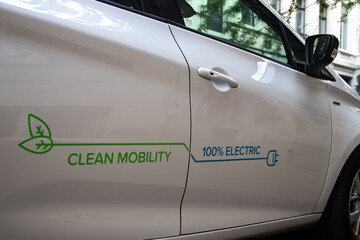 Fototapeta premium Electric vehicle (EV) connected on plug for charging, Clean mobility, 100% electric, reduction of CO2 and green energy, eco and environmental friendly, renewable energy