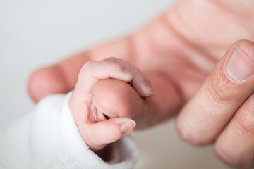 Closeup of a newborn hand and her father finger at hospital on the day of her birth. Fatherhood concept
