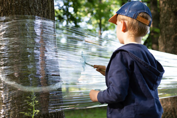 boy paints on stretch film in the woods, perfect time to play
