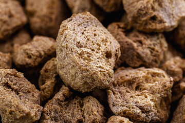pile of soybeans, granulated soy protein on wooden background, food used as a meat substitute in vegan or vegetarian meals.
