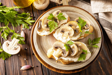 Homemade bruschetta with mushrooms. Toasted sandwich from baguettes bread with soft cheese and grilled mushrooms on wooden rustic table.