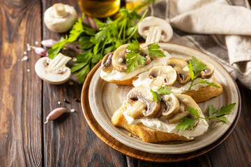 Toasted sandwich from baguettes bread with soft cheese and grilled mushrooms on wooden rustic  table. Homemade bruschetta with mushrooms. Copy space.