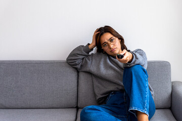 black-haired woman in gray sweater watching boring tv