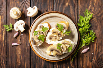 Homemade bruschetta with mushrooms. Toasted sandwich from baguettes bread with soft cheese and grilled mushrooms on wooden rustic table. View from above.