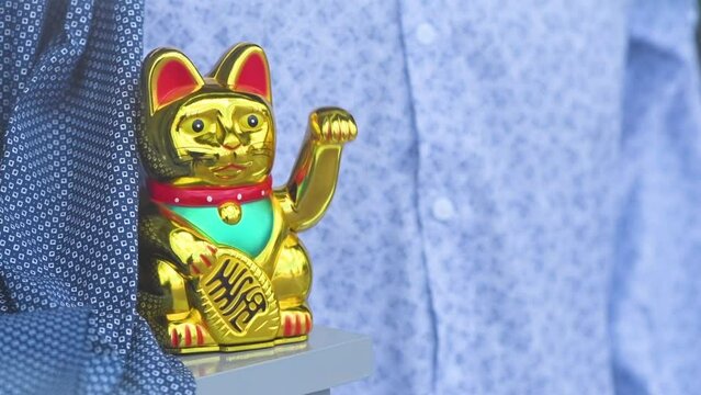 Maneki neko, japanese waving cat adorning the storefront of a trendy clothes boutique. This lucky feline figurine is popular symbol of good fortune and prosperity in Asian culture