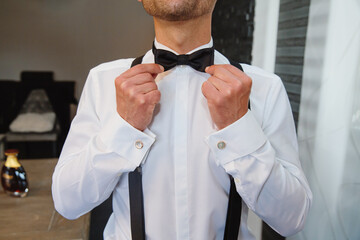 Man fixing his bow tie. Man groom in wedding suit with a bow tie. Close-up.