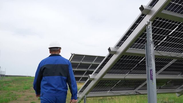 Service Engineer or electrician goes by solar panels, working and solving problem for green energy solar power plant operation. Technician maintenance solar cells on Solar Energy Plant