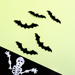 Composition of black bats on an green background and a knitted white skeleton on a black background. Halloween concept.