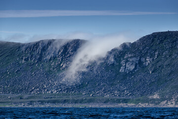Dramatic sea fog rising trough hole in a ridge in Knivskjelodden that the real northernmost point of Europe and close close to North Cape in August 2022.