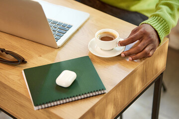 I,age of working desk, table with laptop, notebook, earphone and coffee cup on it. Male hand taking coffee. Concept of business and education, freelance job, modern lifestyle