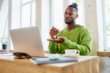 Young businessman, freelancer sitting at home and leading online video call via laptop with colleagues, discussion of projects. Concept of business and education, freelance job, modern lifestyle