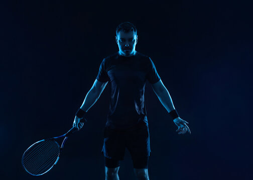 Tennis player banner. Man athlete with paddle tenis racket on black background. Sport concept. Download a high quality photo for sports website.