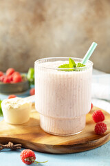 Fresh milk, raspberries drink on wooden board on a stone background, protein shake with fresh berries. Copy space.