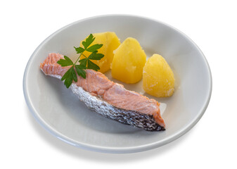 Sliced boiled salmon with potatoes and parsley leaves in white dish isolated