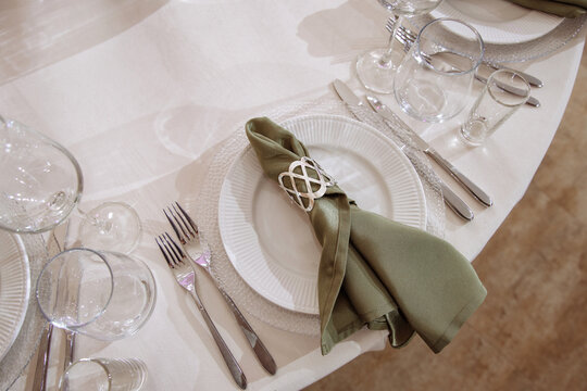 Plates with fabric napkin, decorative ring and cutlery on light gray marble table, flat lay. High quality photo