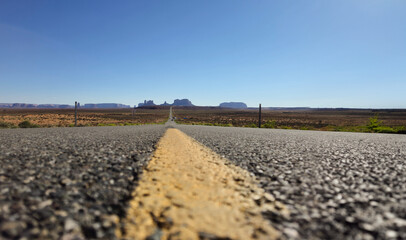 Fototapeta na wymiar Straight road to Monument Valley; on the sides desert landscape with some shrubs