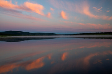 Sunset tranquility, pink clouds reflecting in the still river 
