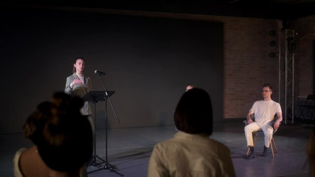 The performance of the girl in front of a small hall. An independent speaker speaks on stage in a conference room for young people. A woman explains motivation to a group of people.