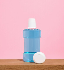 Blue mouthwash and dental floss on a wooden table. Oral care accessories.