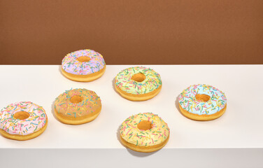 Sweet fresh doughnuts with colored glaze and sprinkles lay on the table. Festive dessert.