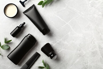 Black cosmetic bottles with green leaves on stone background. Skincare products for men design, branding.