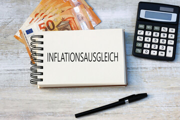 Der Text Inflationsausgleich einem Notizblock mit Eurobanknoten und Taschenrechner.	