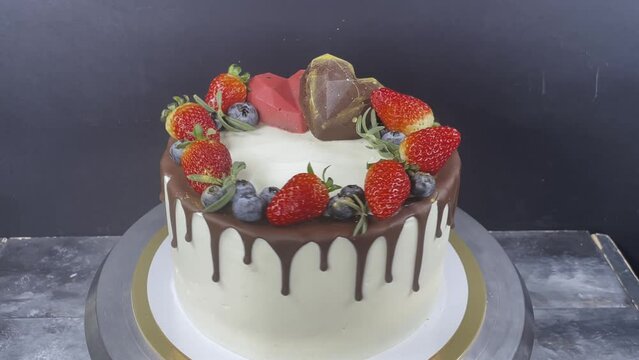 Cake with chocolate drips, strawberry and blueberry on turntable. Cake with hearts. 4k. Wedding cake.