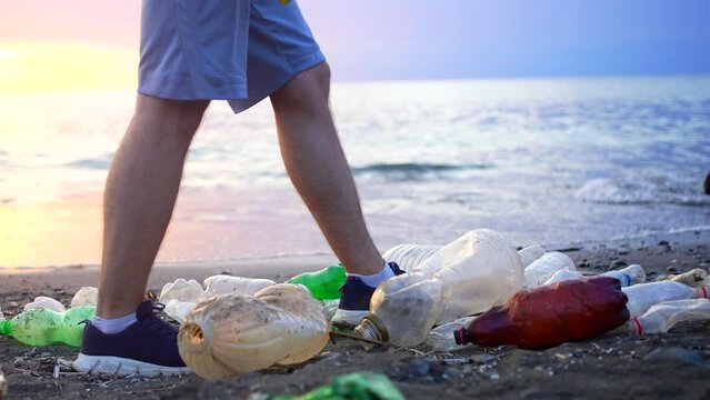concepts the idea of the problem of plastic garbage ,pollution of the world ocean the legs of a man walking along the seashore
