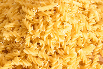 Uncooked Fusilli Pasta Scattered on Wooden Board and White Table. Raw and Dry Macaroni. Fat and Unhealthy Food