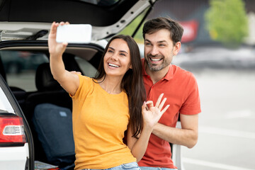 Fototapeta na wymiar Happy couple travellers taking selfie next to open car trunk