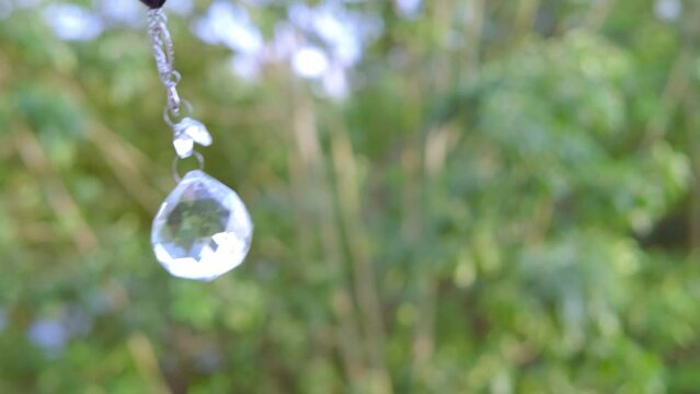 Woman hand holding and using glass ball crystal ball pendulum and using, female hands with crystal glass ball close-up on green natural background, pendulum swings, Magic and Spiritual Awakening