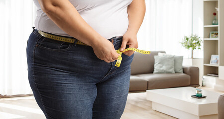 Obese woman wearing jeans and measuring waist