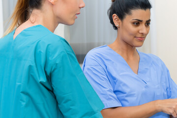Dos enfermeras viendo a su paciente en la consulta de un hospital - obrazy, fototapety, plakaty