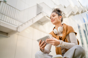 Young adult Caucasian woman sit on bench outdoor use digital tablet