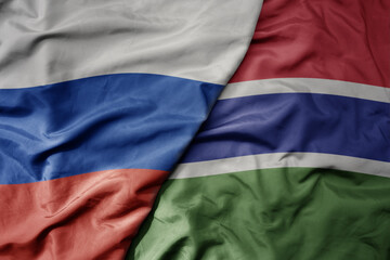 big waving realistic national colorful flag of russia and national flag of gambia .