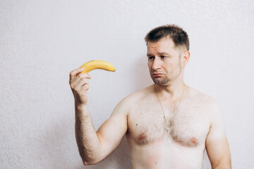 A man holds a banana in his hand. Potency problems. guys health