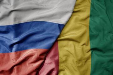 big waving realistic national colorful flag of russia and national flag of guinea .