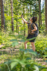 Naklejka na ściany i meble woman hiker takes a self-portrait with her phone in the woods on a sunny day