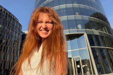 Fototapeta na wymiar Portrait of young happy beautiful woman with red hair, businesswoman in business centre or college student at campus looking at camera and smile 